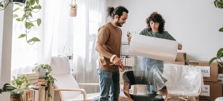 a couple using bubble wrap to pack a chair