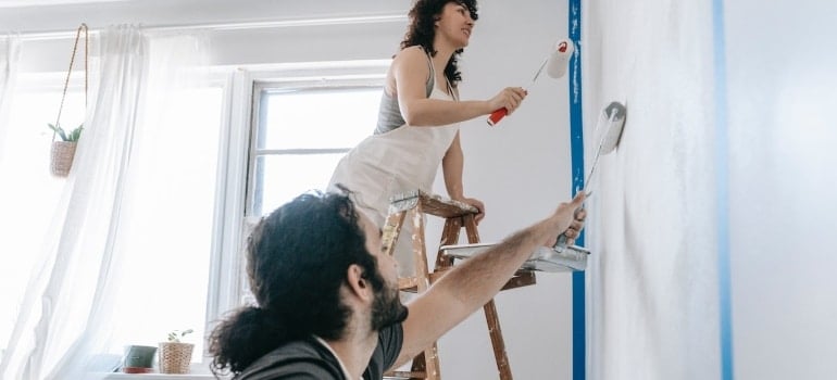 a couple painting the wall while arranging a Coconut grove apartment