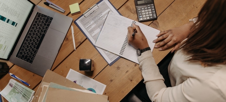 A woman calculating the costs of living of Edgewater vs Wynwood