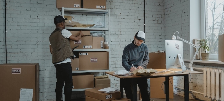 two men surrounded by boxes, about to arrange an office, 