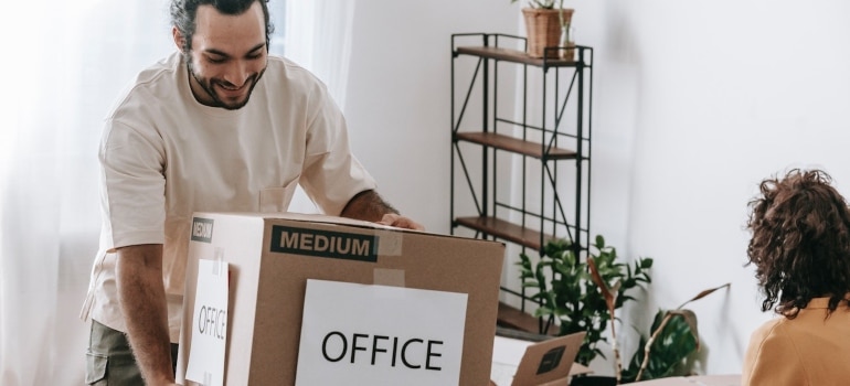 a man carrying a box labeled office after hiring commercial moving services