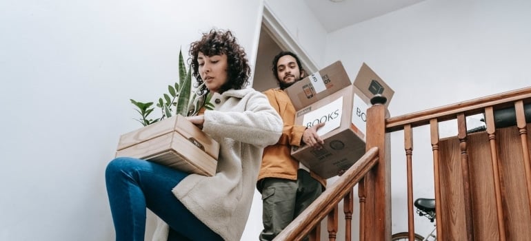 a couple carrying boxes and plants