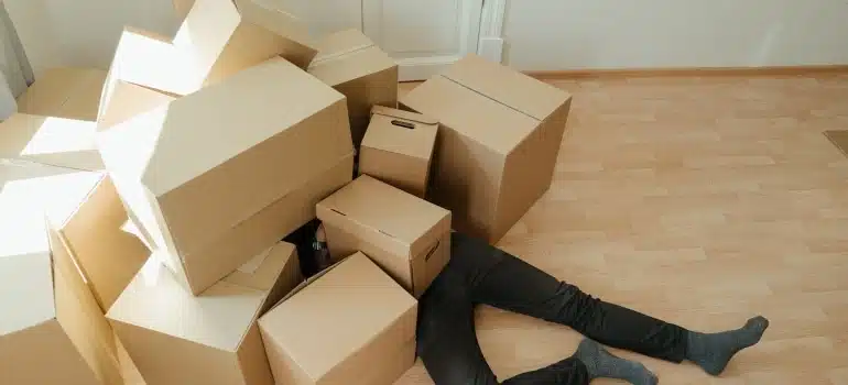 a man under a bunch of boxes ready for moving ivng after hurricane