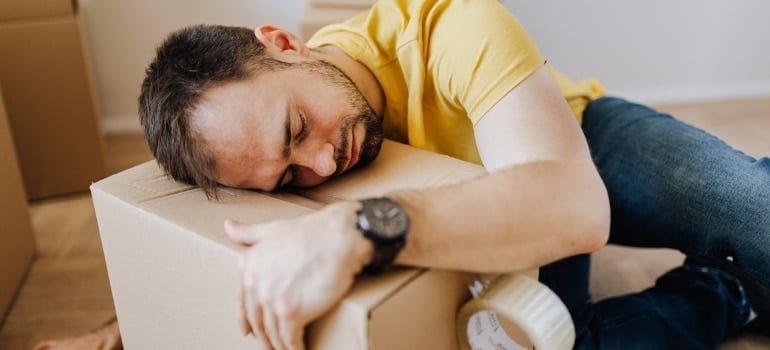 a man falling asleep on the moving box emotionally preparing for leaving Doral