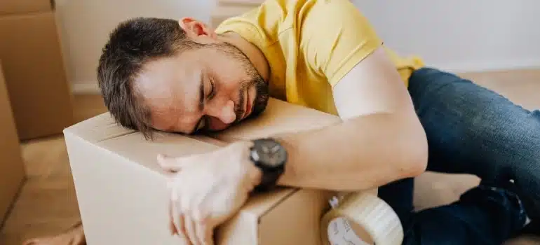 a man falling asleep on the moving box emotionally preparing for leaving Doral