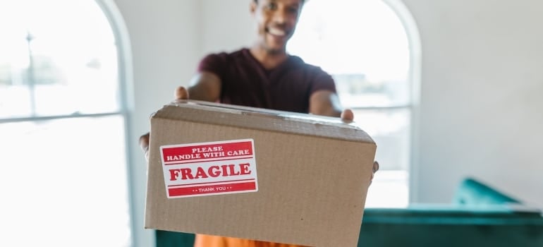 a man holding a box labeled fragile and about to pack your condo when moving to Miami Beach