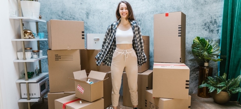 A happy woman surrounded by boxes after decluttering when moving to Aventura
