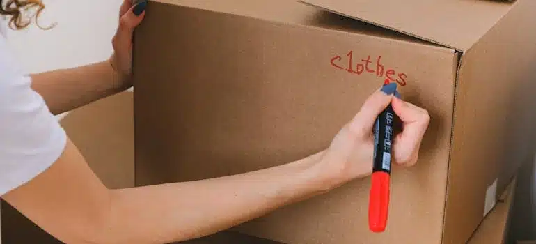 A woman writing label on a box with a marker