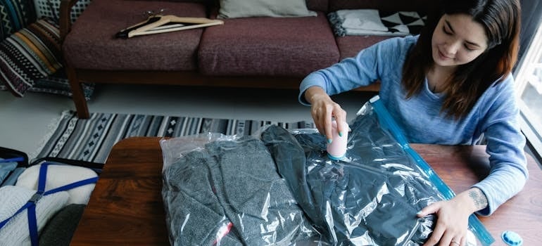 A woman vacuum packing clothes on a table
