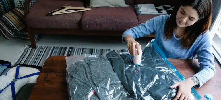 A woman vacuum packing clothes on a table