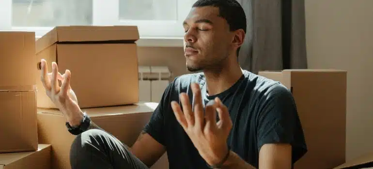 a person surrounded by boxes meditating before moving to Coral Springs on a short deadline