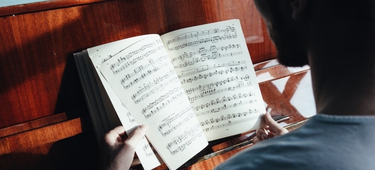 a man sitting at a piano and reading the musical notebook