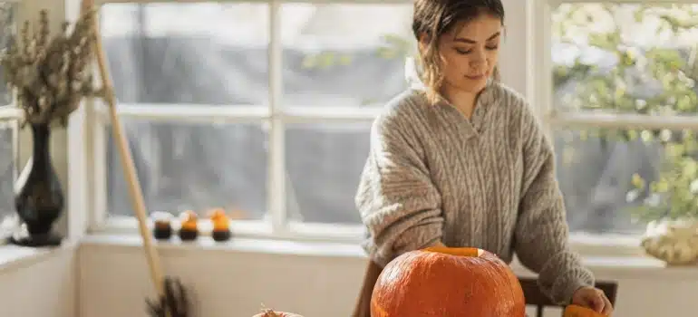 a woman carving a pumpkin for the  best Halloween housewarming party ideas