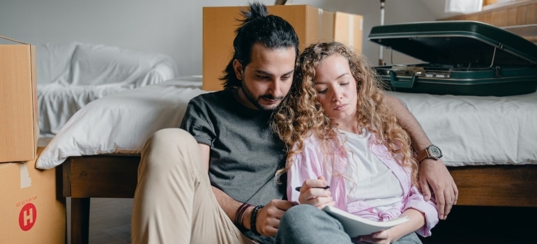 a couple making a floor plan surrounded by boxes