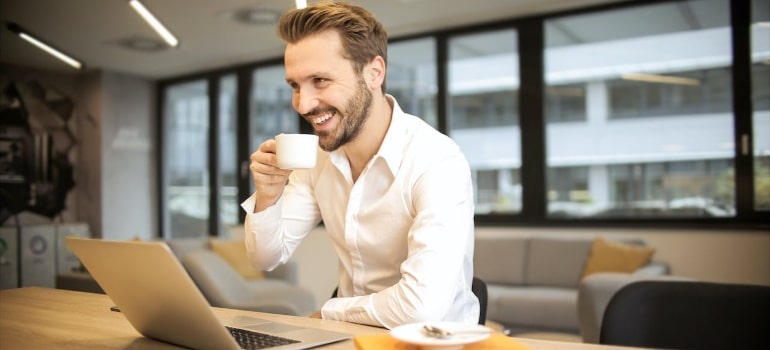 a person drinking coffee in front of laptop