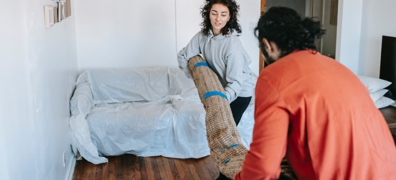 a couple lifting a carpet