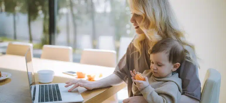 A woman holding a baby and reading an article o a laptop about living on Indian Creek 