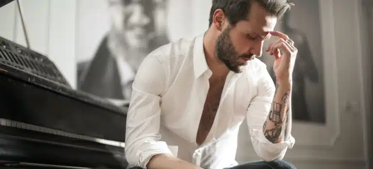 a man next to a piano thinking about moving an antique piano