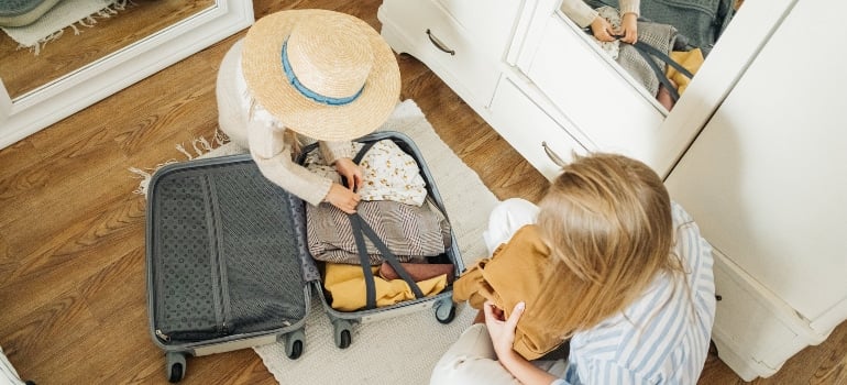 Mum and little girl packing suitcase for moving from South Point to Sunny Isles Beach
