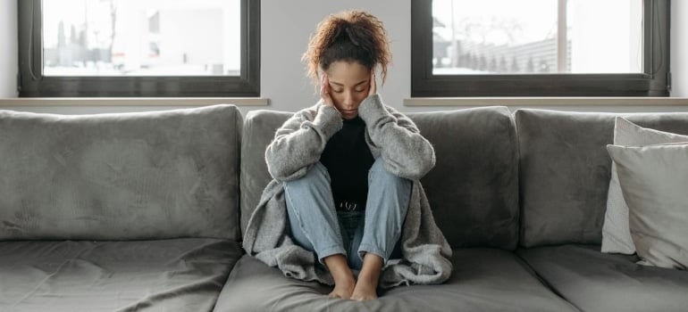 a woman sitting on a sofa thinking about how to overcome homesickness when moving out of Florida