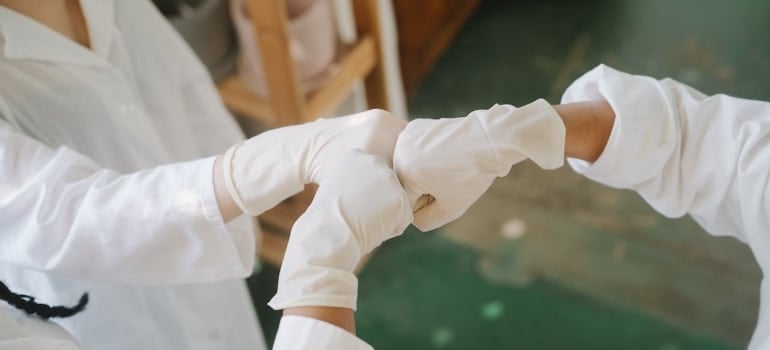 People Wearing White Latex Gloves Doing Fist Bump