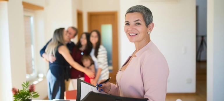 A family hugging and a happy real estate agent