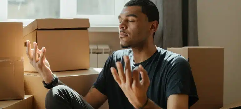 a man meditating surrounded by boxes