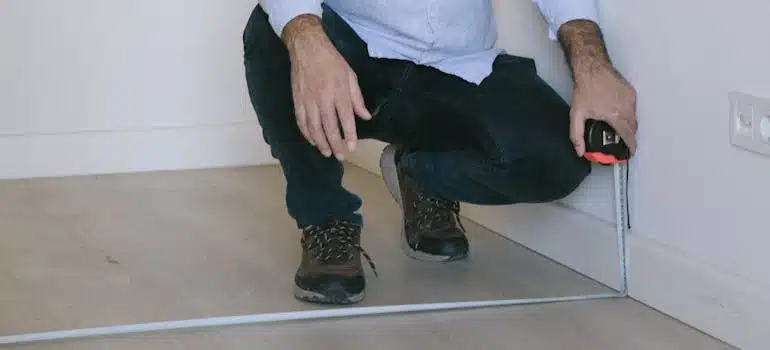 A man measuring wooden floor