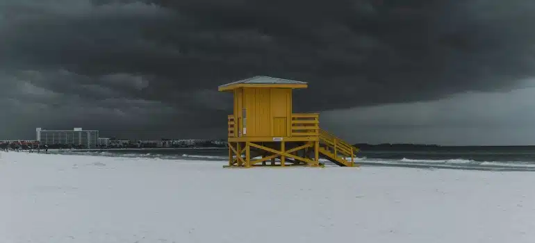 A yellow lifeguard tower on an empty sandy beach before thunderstorm in Siesta Key thanks to Florida weather guide