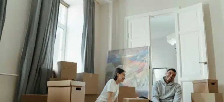 a couple surrounded by boxes talking about moving services to use when relocating a fine art gallery