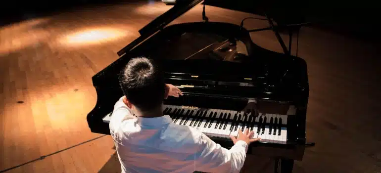 a man sitting at a grand piano thinking about how to move musical instruments long distances 