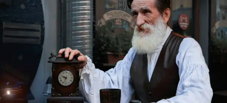 an old man next to a clock thinking baour relocating antique clocks to Pompano Beach