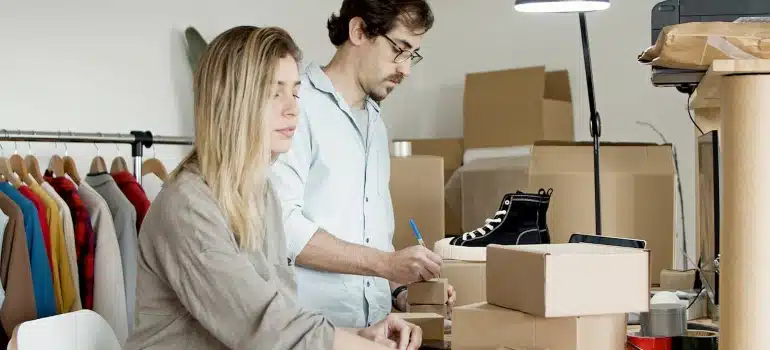 two people packing in order to relocate a fashion store to Pompano Beach