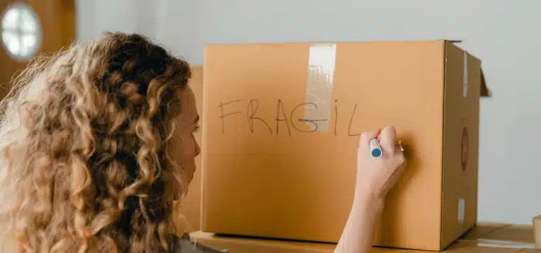 a woman labeling a box fragile