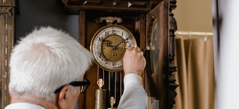 A man setting time after relocating antique clocks to Pompano Beach