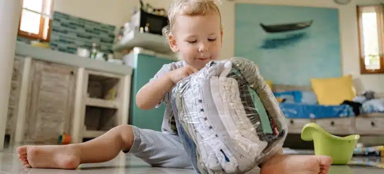 toddler playing with a bag of clothes