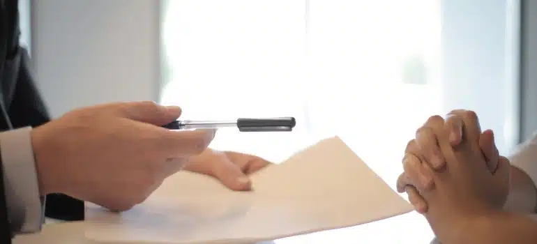 a person handing a pen and paper to another person