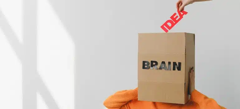a box labeled brain and a hand holding a sign "idea"