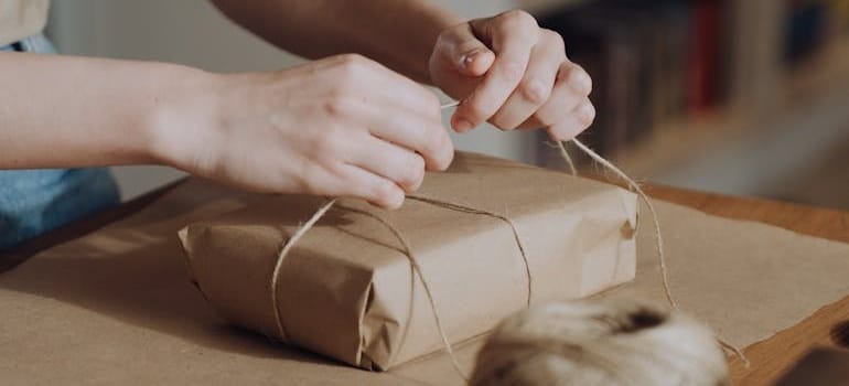 A person as they reuse packing materials to wrap a present in packing paper
