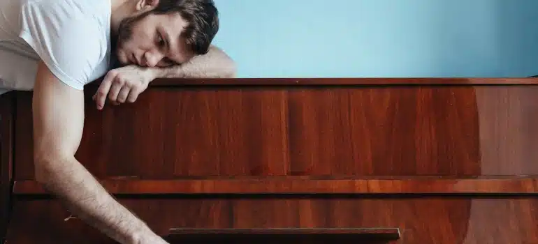 a man leaning on a piano thinking about how to relocate an antique piano from Brickell to Marathon