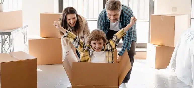 Parents reuse packing materials playing with a kid in a moving box