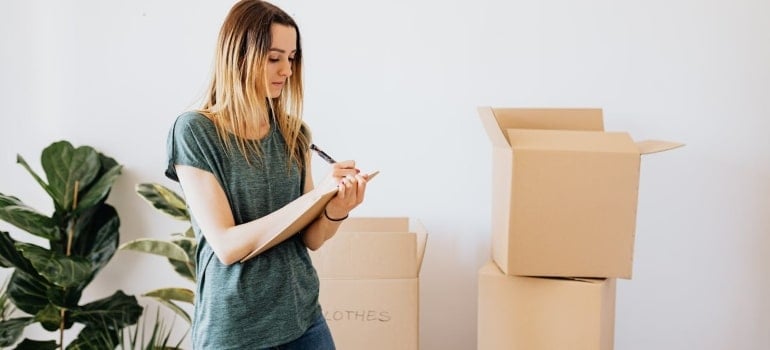 a woman writing an inventory as a part of moving day etiquette