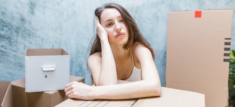 a woman surrounded by boxes thinking about how Miami storage makes DIY moving easier