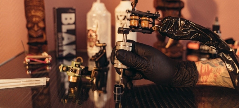 A Person Wearing Gloves Holding Tattoo Machine