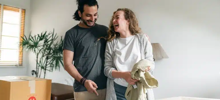 a couple smiling next to boxes thinking about how to save space when packing for a move 