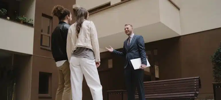 A couple talking to an agent in front of a building