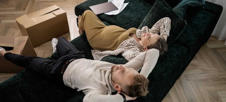 a man sitting on a sofa next to a pregnant woman