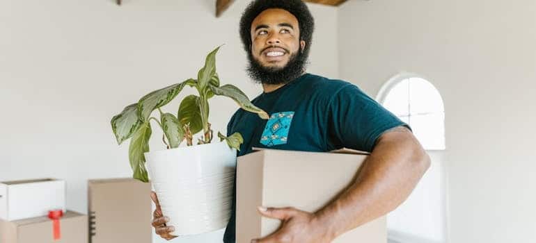 a mover holding a plant and a box before loading a moving truck