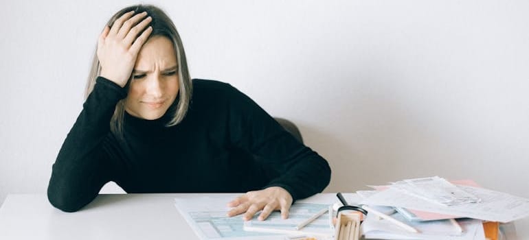 a woman having a headache while dealing with issues when moving antique furniture internationally
