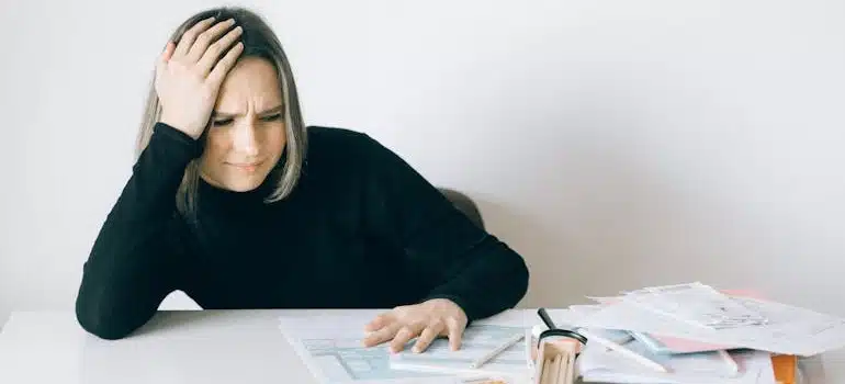 a woman having a headache while dealing with issues when moving antique furniture internationally